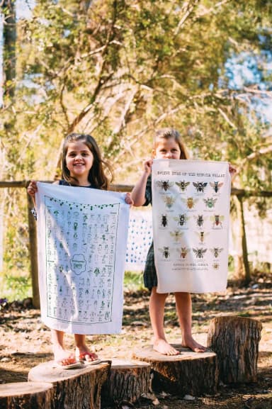 Two children holding up their school’s printed tea towels