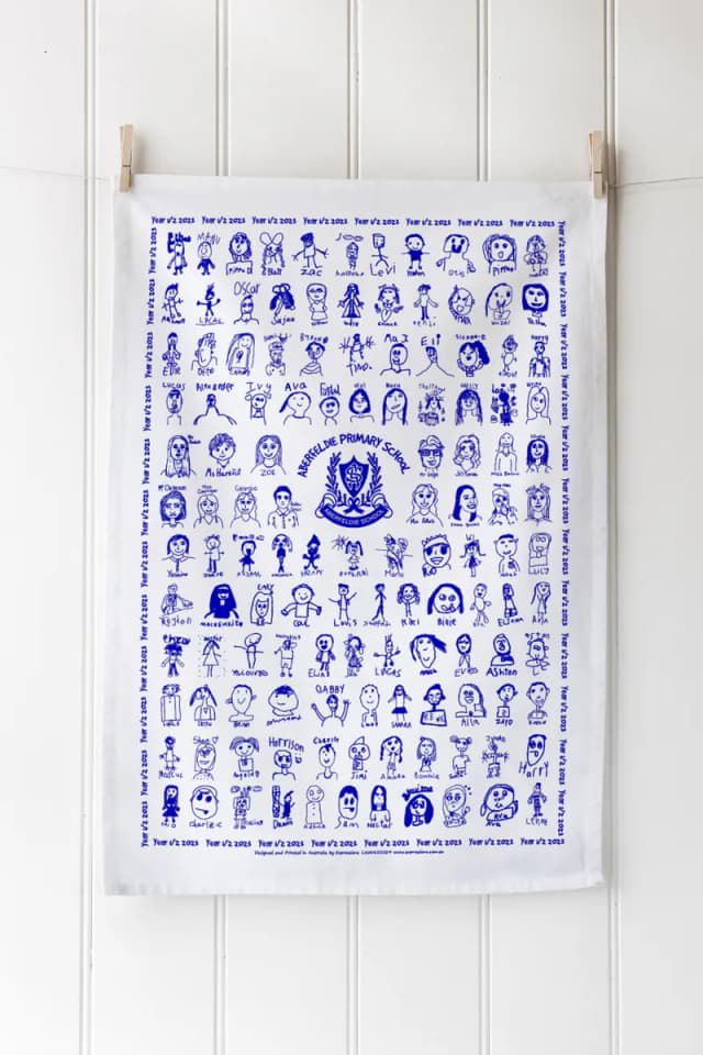 A tea towel screen printed in blue with a school’s self-portraits