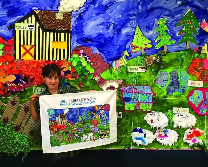 A student holding a tea towel printed with a school mural